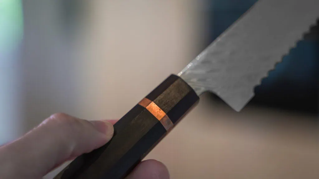 Test af Jørgsholm knive: Er de pengene værd? Billede Nærbillede af trægreb på Jørgsholm kniv og kobber ring